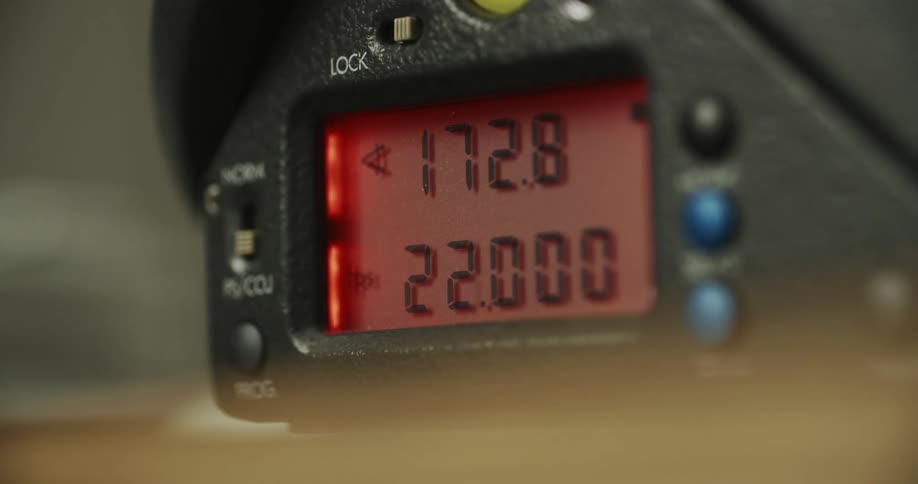 An electronic device with a screen showing two rows of numbers the lower of which rises