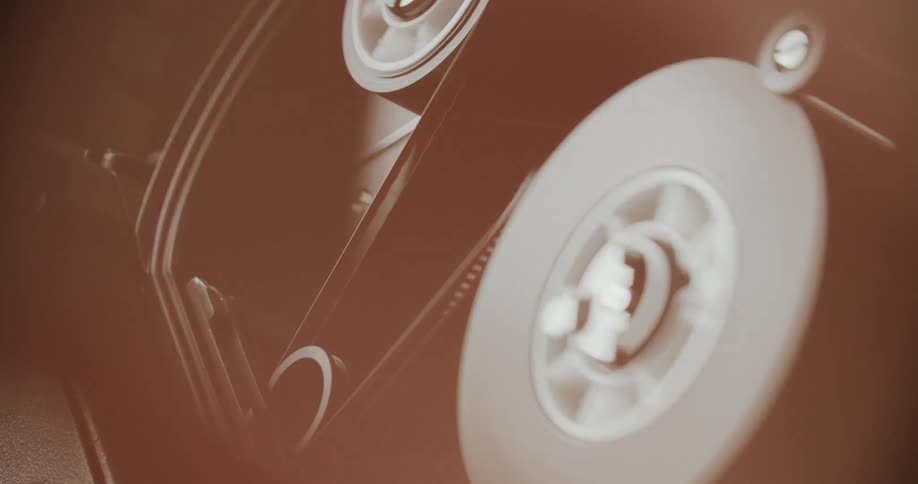 Closeup of the reels and tape of an analog film camera in warm tones