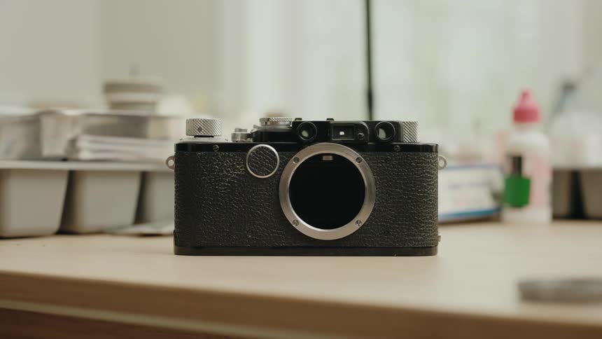 Analog camera without lens on a work table with tools and jars in the background