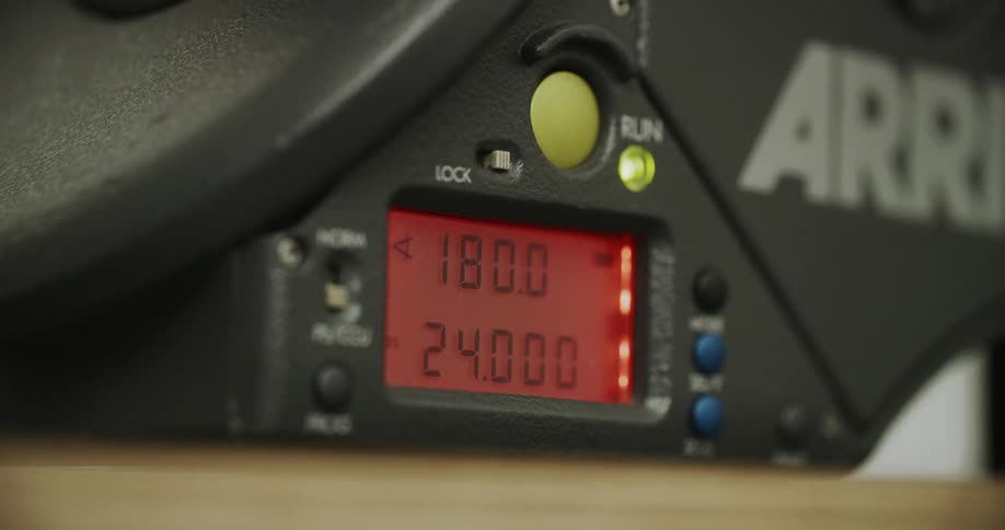 Closeup of an electronic panel with a red display showing numbers while a finger presses a yellow button