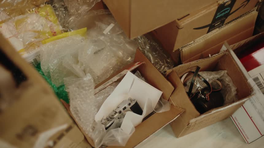 A cluttered pile of cardboard boxes and plastic packaging contains various items