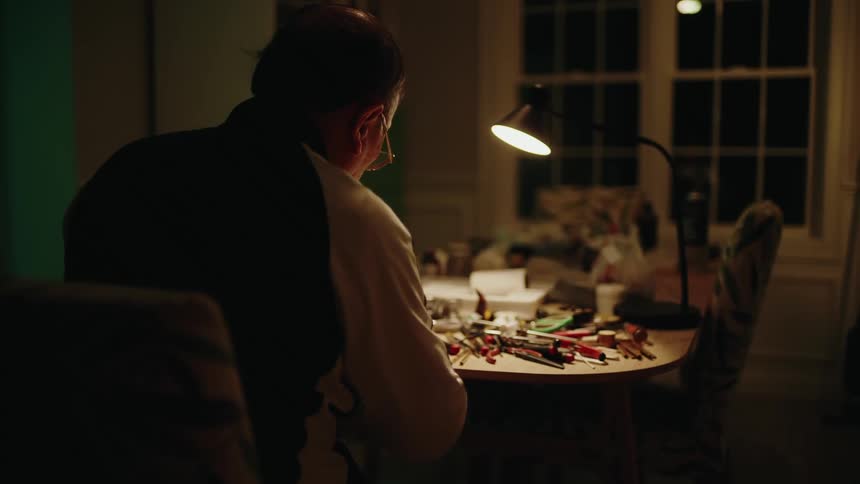 Elderly man sitting at table working at night