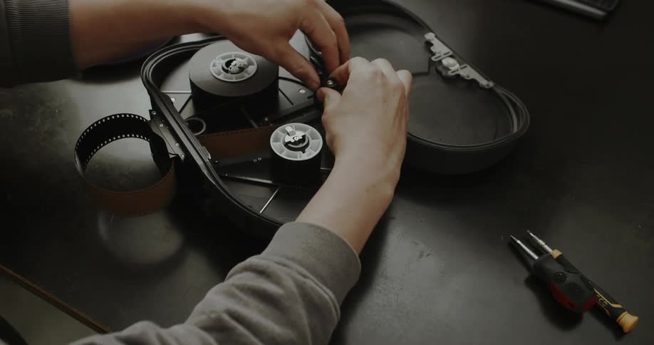 Person handles a roll of film inside an open analog camera on a work table