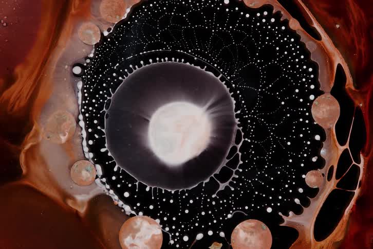 Ink expands and contracts into black fluid bordered by rust colored edges