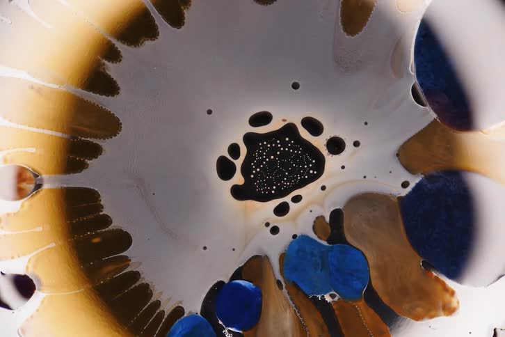 Abstract mixture of liquids in shades of blue gold and black forms organic patterns and fluid textures