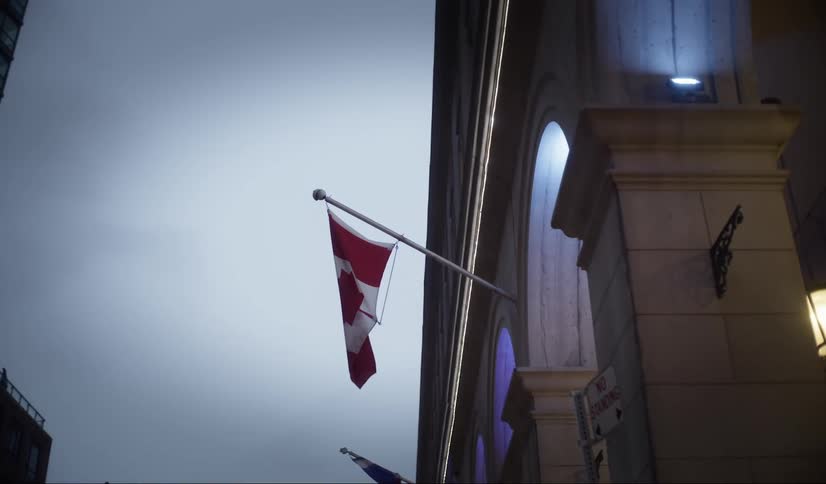 Canadian flag fluttering in the wind fixed on the illuminated facade of a classical architecture building