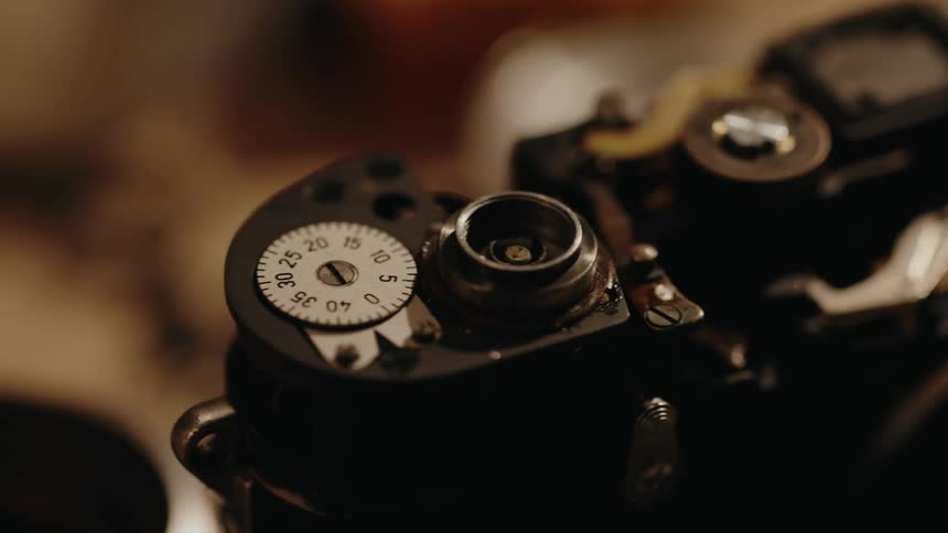 Vintage analog camera closeup highlights its metallic and mechanical details under a warm light