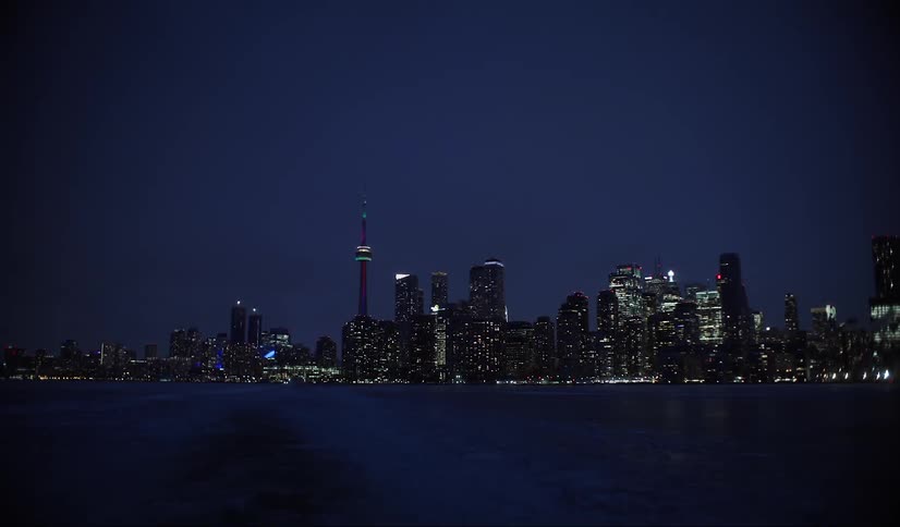 Skyline of an illuminated city reflects on the water at night