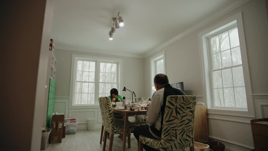 Two people work on their crafts while sitting in a room at home