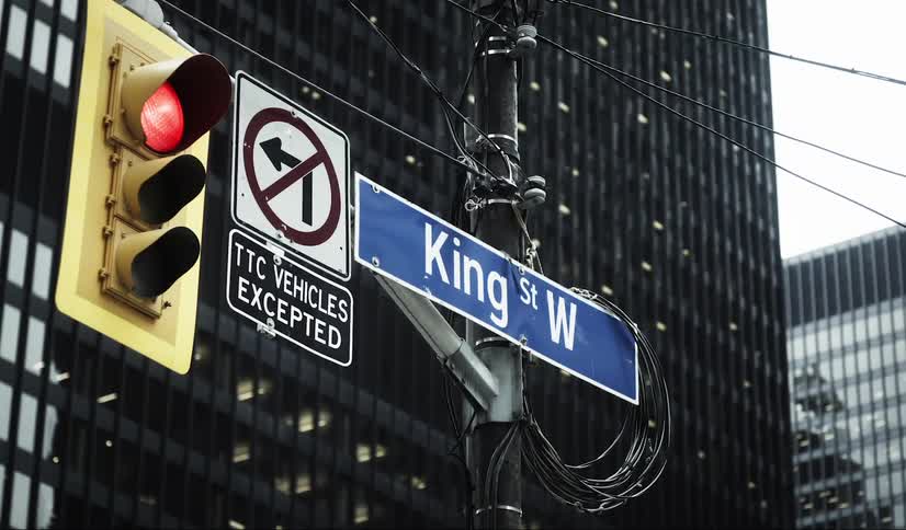 Street sign indicating king st w is attached to a pole with a red traffic light