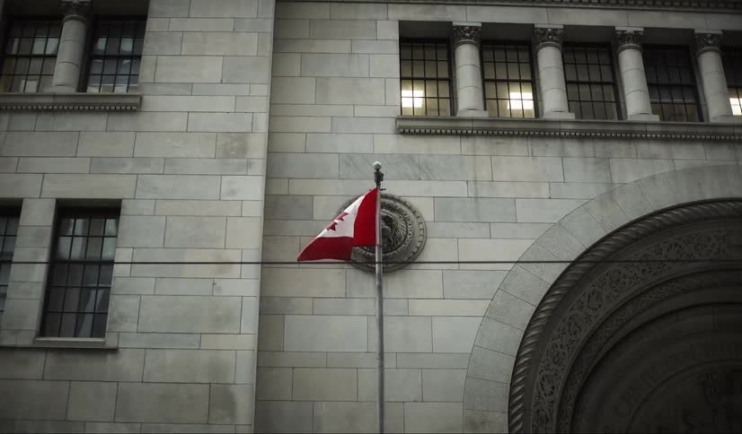 Canadian flag on a flagpole in front of a classic building