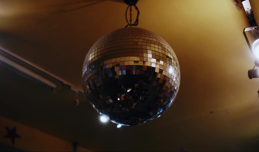 Shiny disco ball spinning rapidly from yellow ceiling