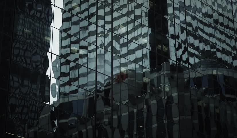Distorted reflections of neighboring buildings spread across the mirrored facade of a skyscraper