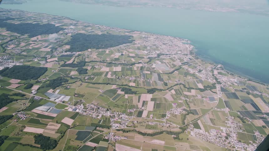 Aerial view of a rural area with cultivated fields near a large body of water