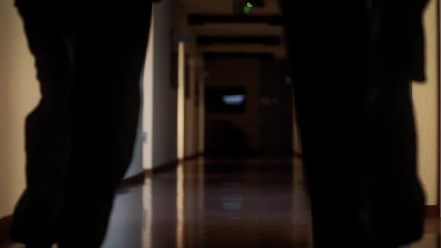 Silhouette of two people walking down a hospital corridor