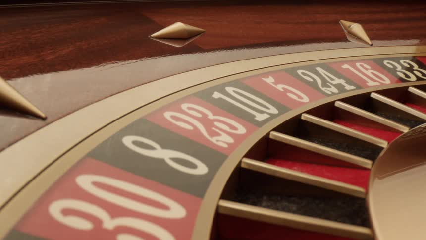 White ball rolling along the surface of a rotating roulette wheel bounces across multiple slots