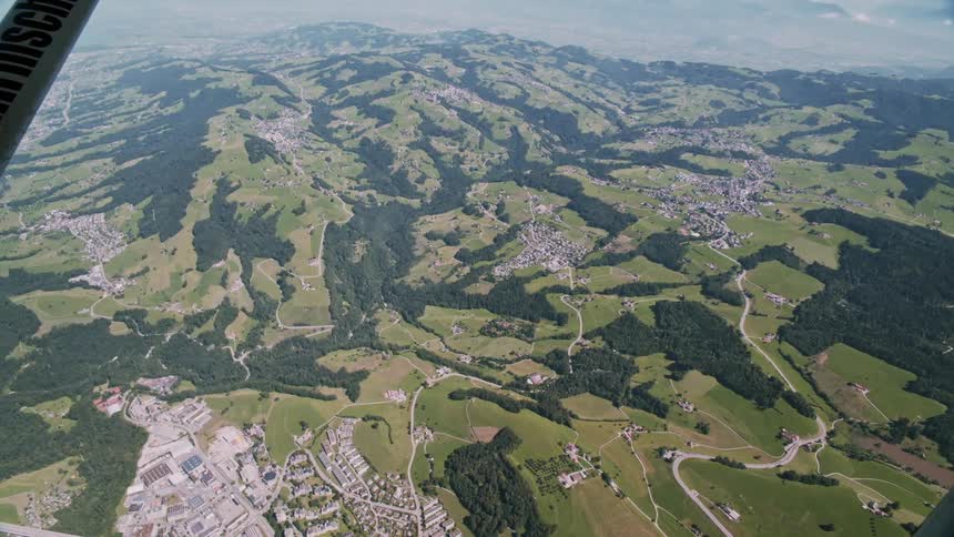 An aerial view of a city located between several green hills
