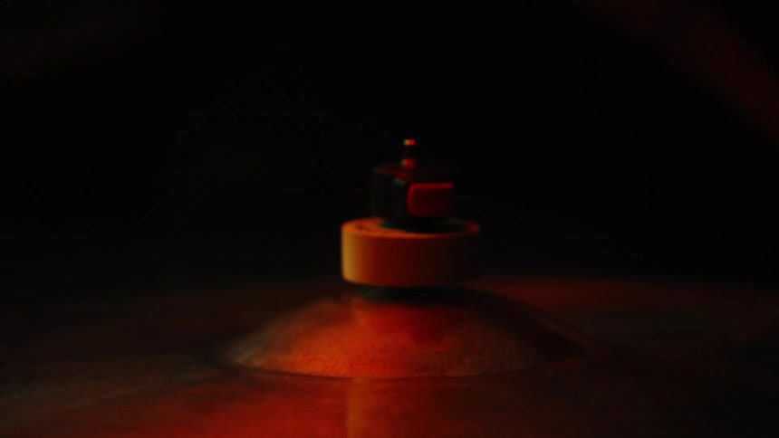 A cymbal being struck by a stick under flashing colorful lights against a dark background