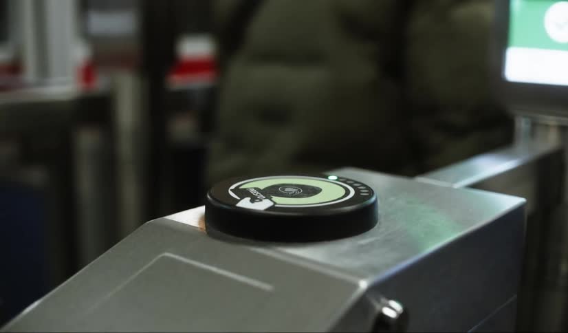 Hand inserting card into a turnstile at a train station
