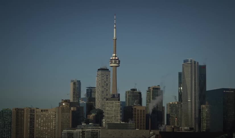 The cn tower rises above the toronto skyline against a clear blue sky