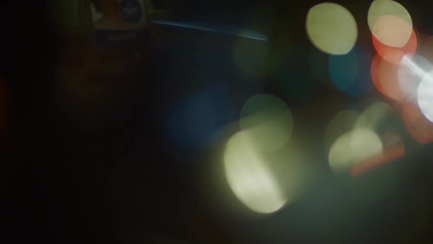 A stream of blurred multicolored orbs of light streaks across a dark background