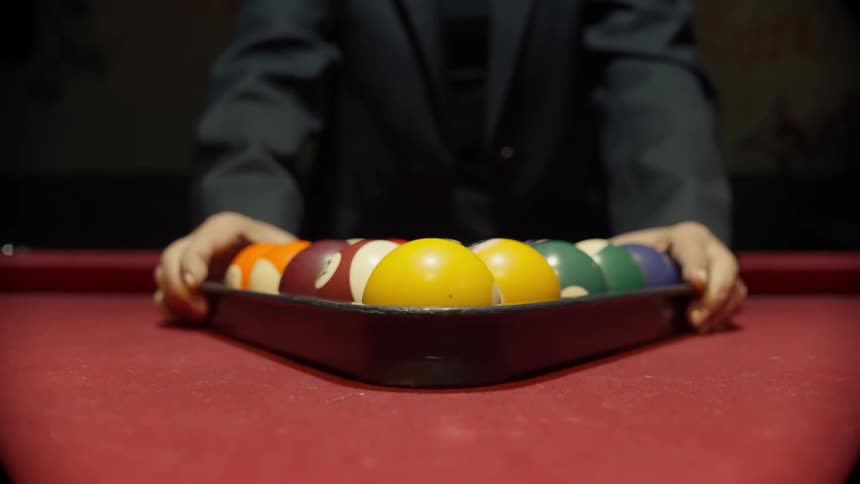 Pair of hands arranging pool balls in a triangle