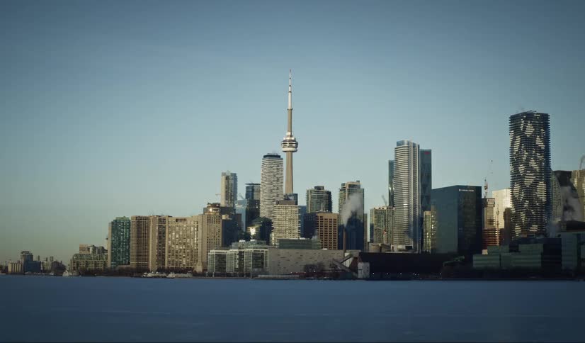 The sun rises over the toronto skyline against a clear blue sky