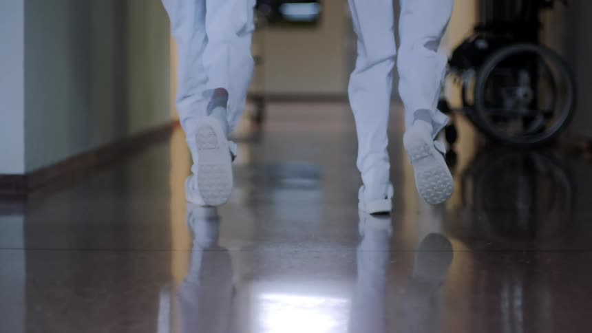 Legs of two people running in a hospital hallway