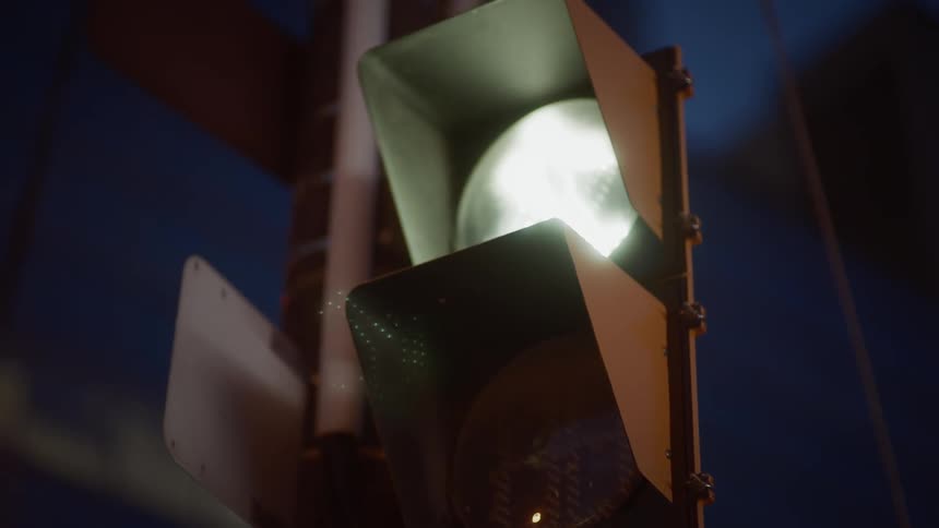 A glowing white light on a traffic light mounted on a pole with signs