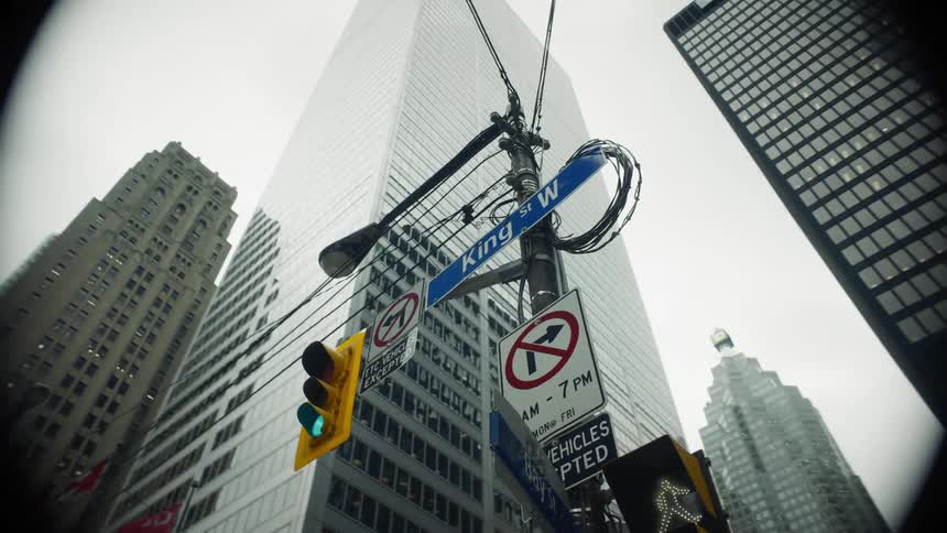 Traffic light with green signal for vehicles in the middle of a metropolis with skyscrapers