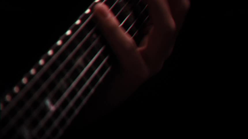 A persons fingers frantically playing with the strings of a musical instrument