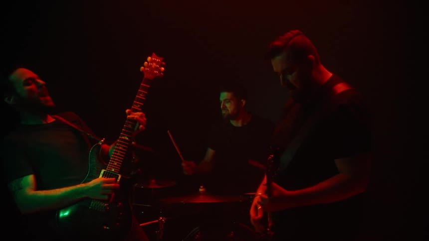 Two guitarists and a drummer in a performance