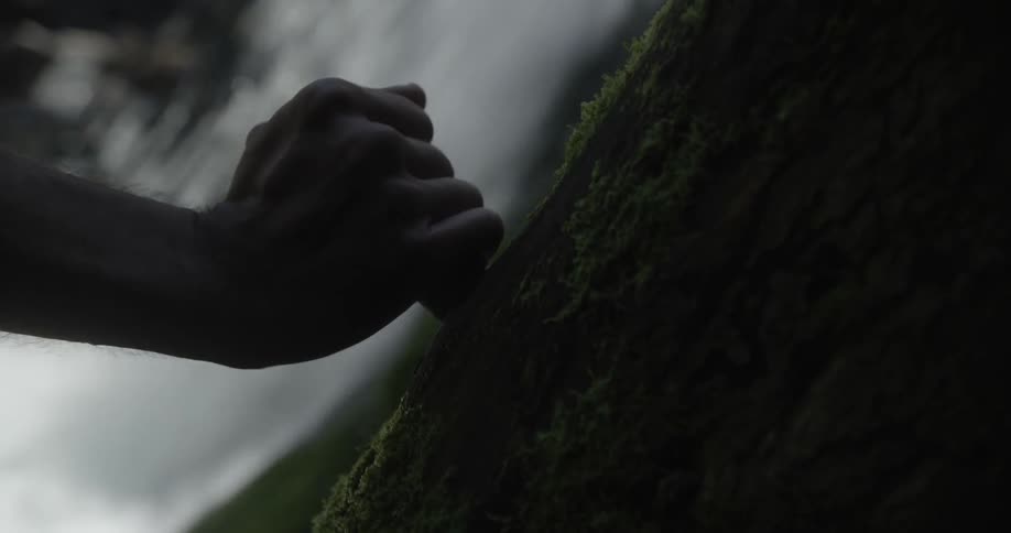 Hand holds an iron as it moves towards a waterfall