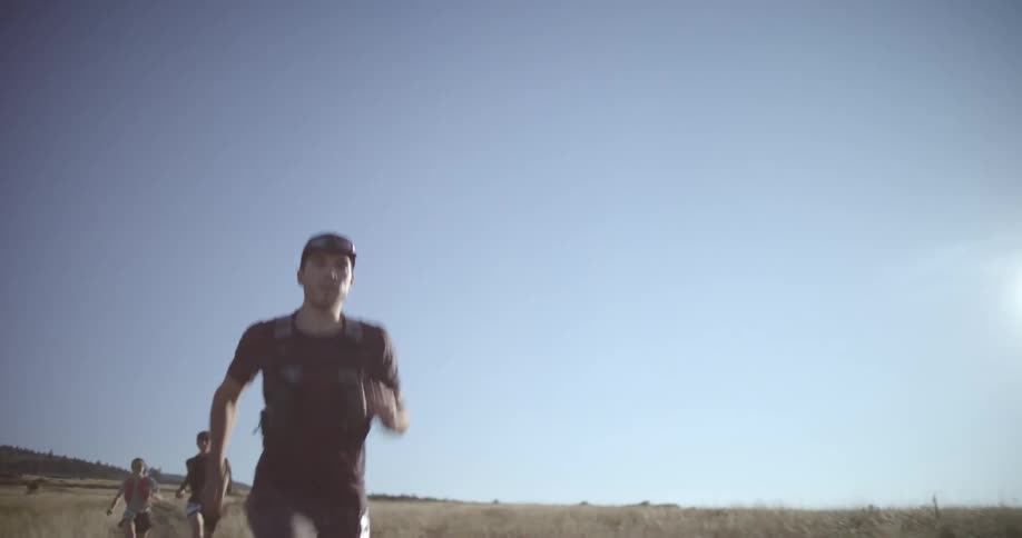 Group of runners cross an open landscape under a clear blue sky