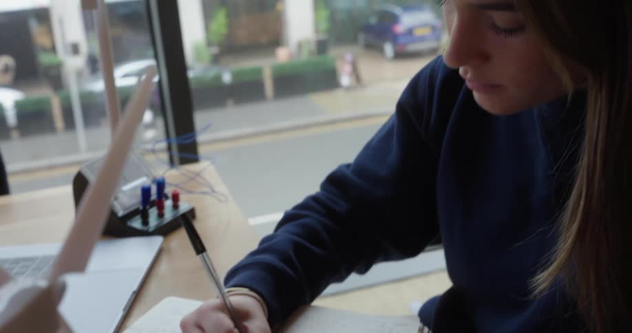 Young woman sitting at a table drawing a wind energy platform