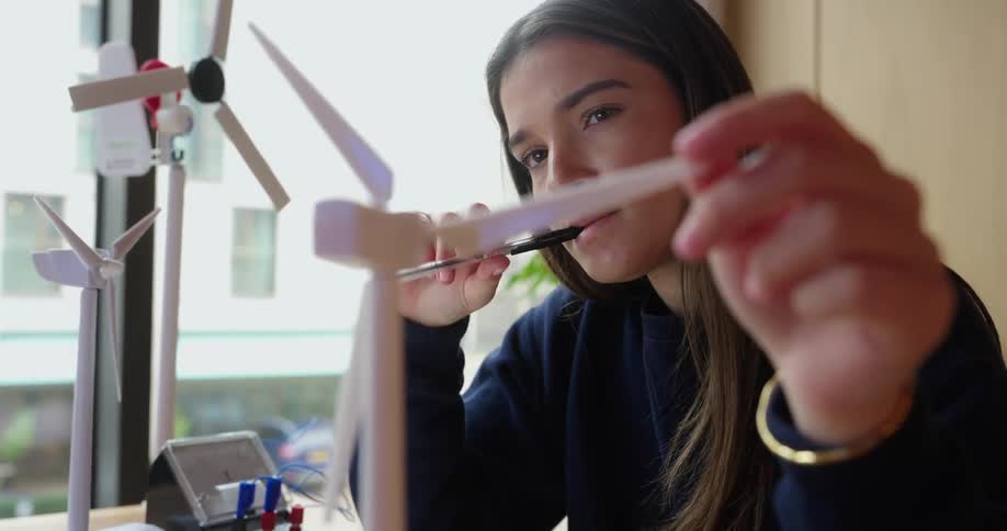 Young woman sitting interacting with a wind power engine model