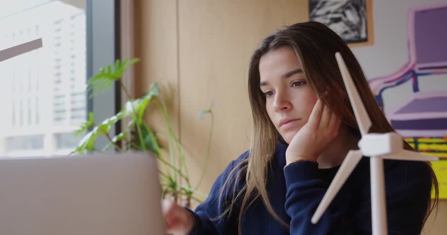 Concentrated woman sitting at a table in front of a laptop