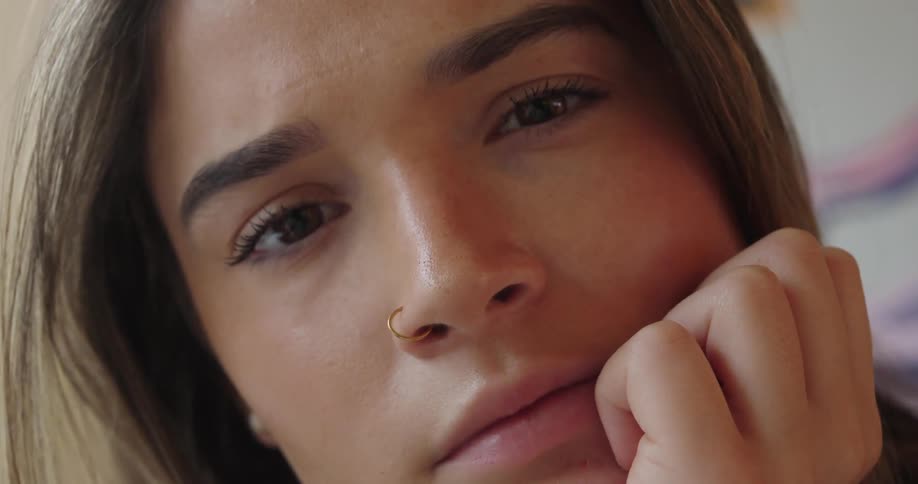 Woman looks intently at something out of focus while resting her face on her hand