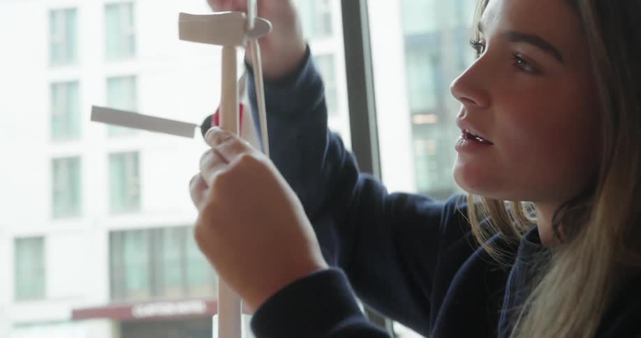 Young woman sitting holding and interacting with a small wind power model