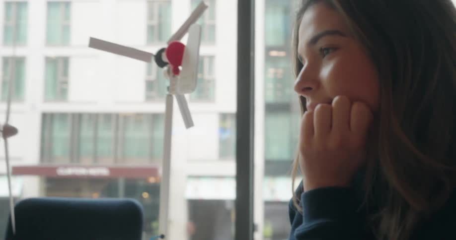 Woman looks closely at a model of a wind turbine while pointing at a computer screen