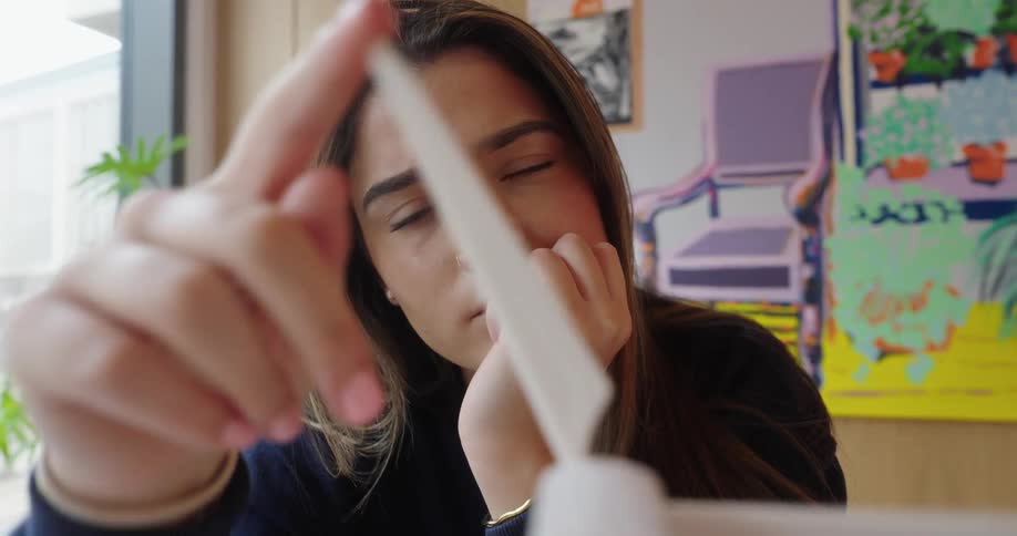Woman looks closely at a model wind turbine while touching one of its blades