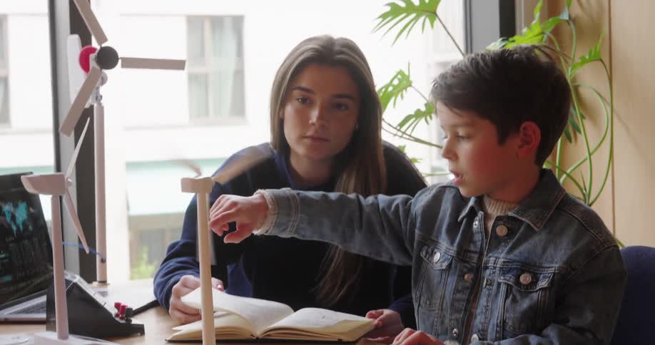 Teenage girl watches a boy working with wind turbine models