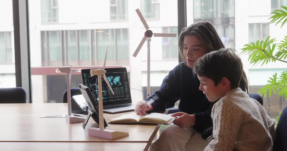 Woman holding a pen and cheerfully explaining to a boy next to her