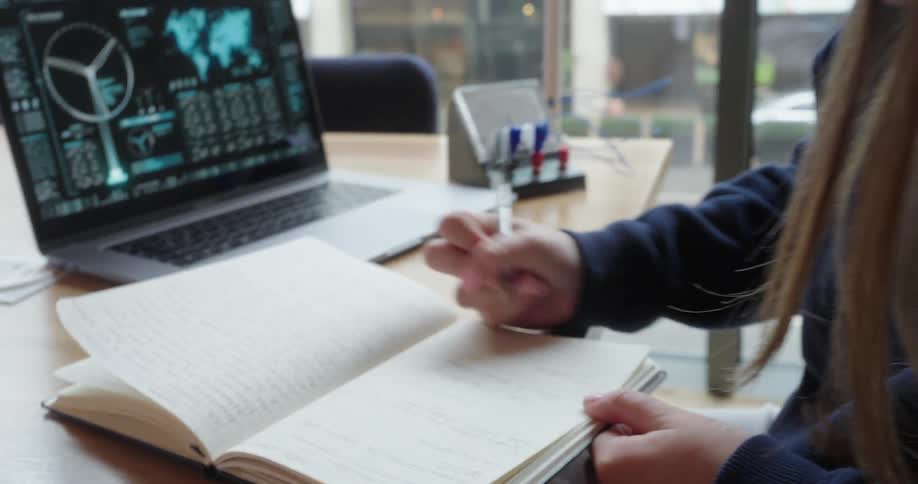 Woman leaning over desk writing and analyzing renewable energy graphs