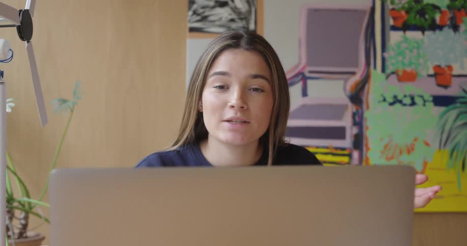 The face of a young woman who is talking while looking at a laptop