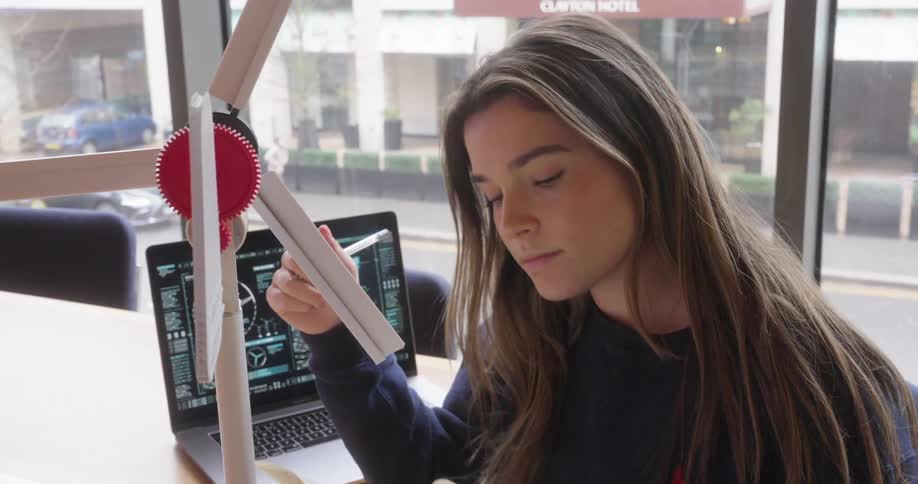 The face of a young woman who is spinning a device with some small propellers that is in front of her