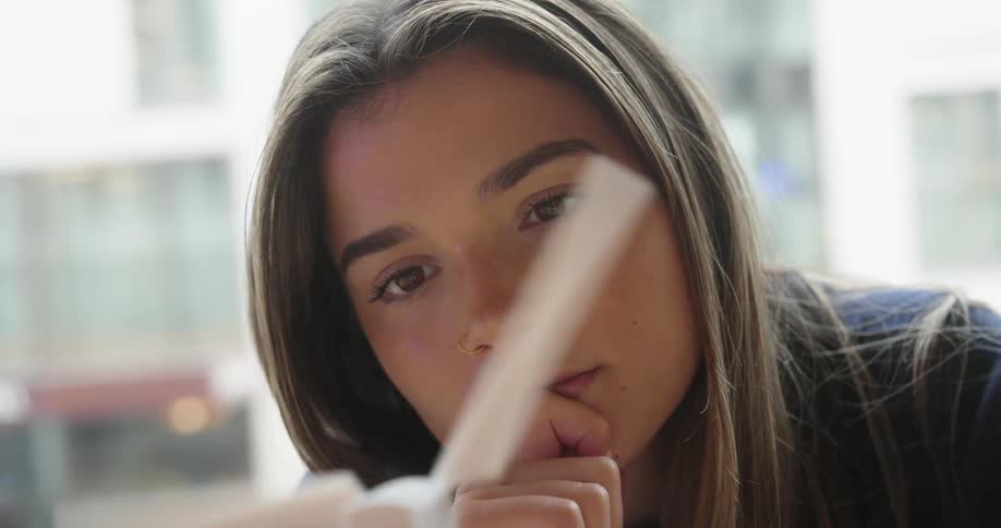 Young woman watches intently as the blades of a model wind turbine spin in front of her