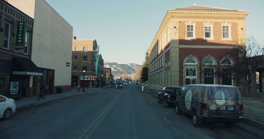 Busy street in a small town with historic buildings and parked cars at dusk