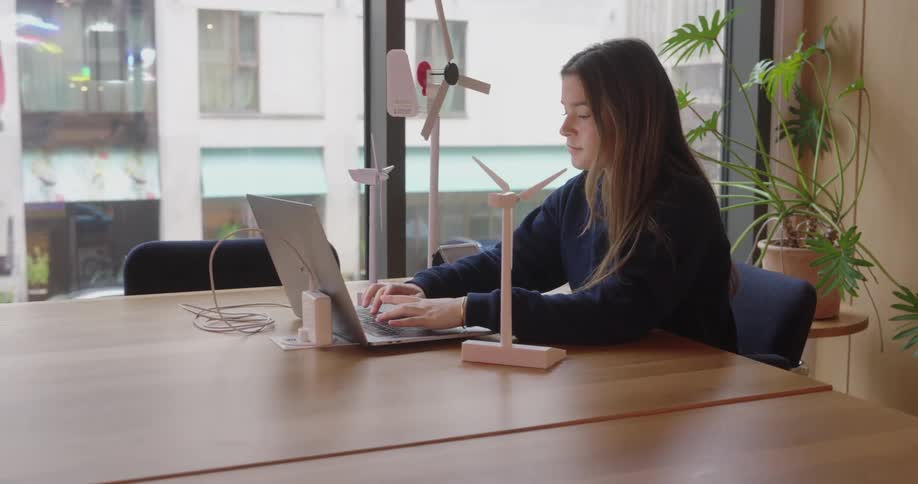 A young woman sits in a conference room and types on her laptop