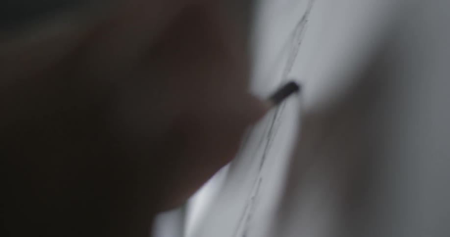 Close up of hand drawing with charcoal over paper in a studio